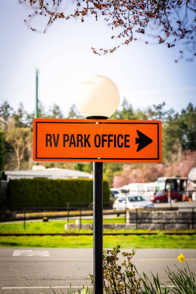 Bright orange RV Park Office sign with right arrow at Fort Victoria RV Park.