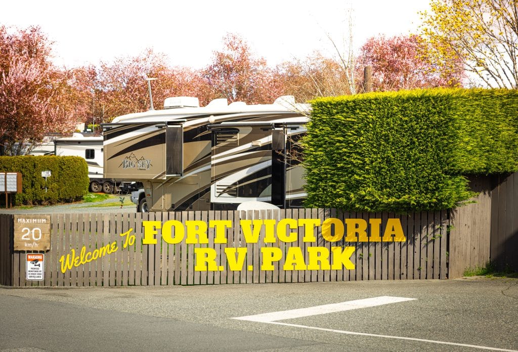 Color photo of the Fort Victoria RV Park entrance sign with RVs in the background.