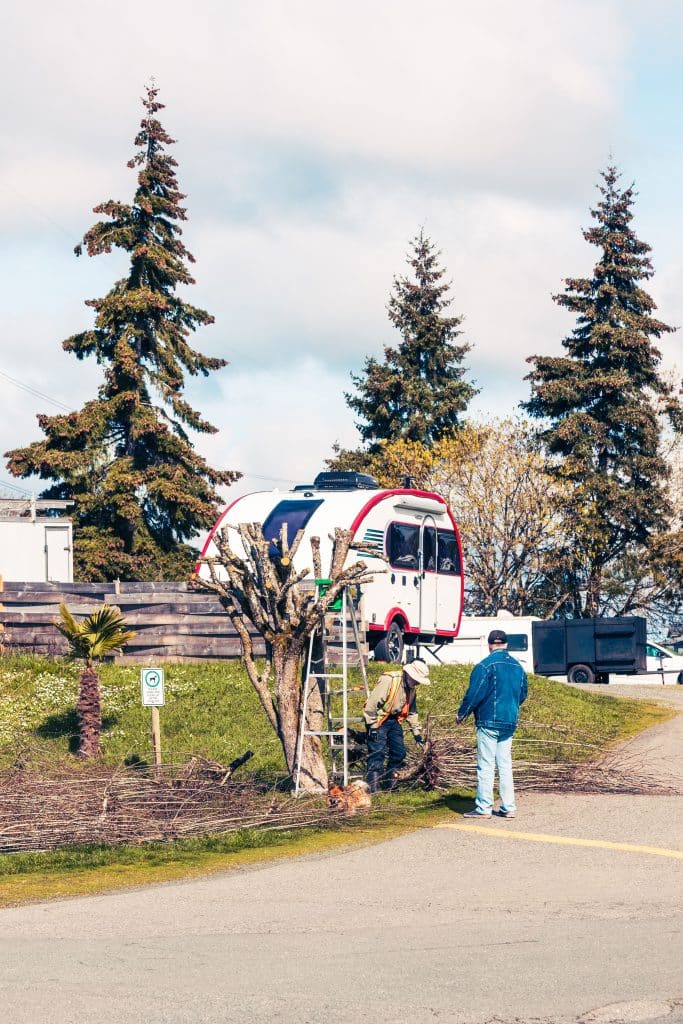 Guests tending to landscaped gardens at Fort Victoria RV Park with RVs in the background.