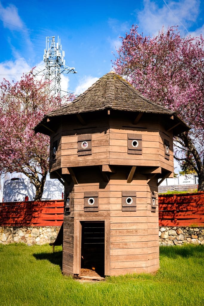 Color photo of the historic blockhouse tower at Fort Victoria RV Park with spring blossoms.